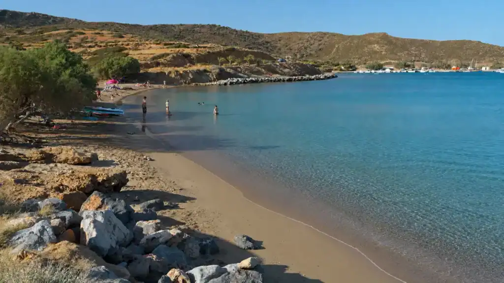 Swimmers wading in the calm bay at Kouremenos, among the best beaches near Vai beach