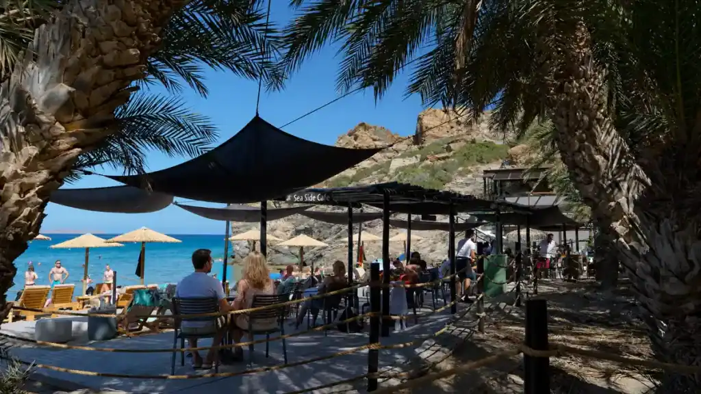 Diners under palm trees at Sea Side Cafe overlooking Vai bay