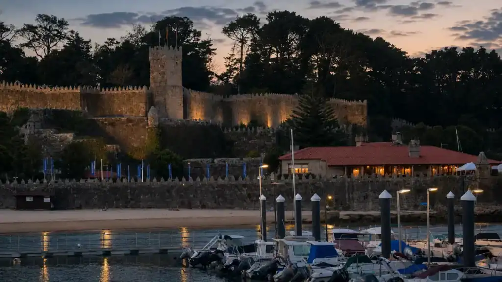 Floodlit walls and tower of Monterreal Castle rising above the marina at twilight