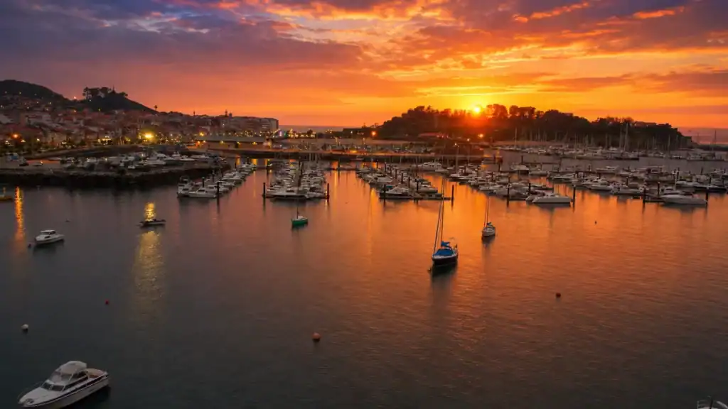 Fiery sunset over Baiona marina with sailboats moored and Monterreal peninsula beyond