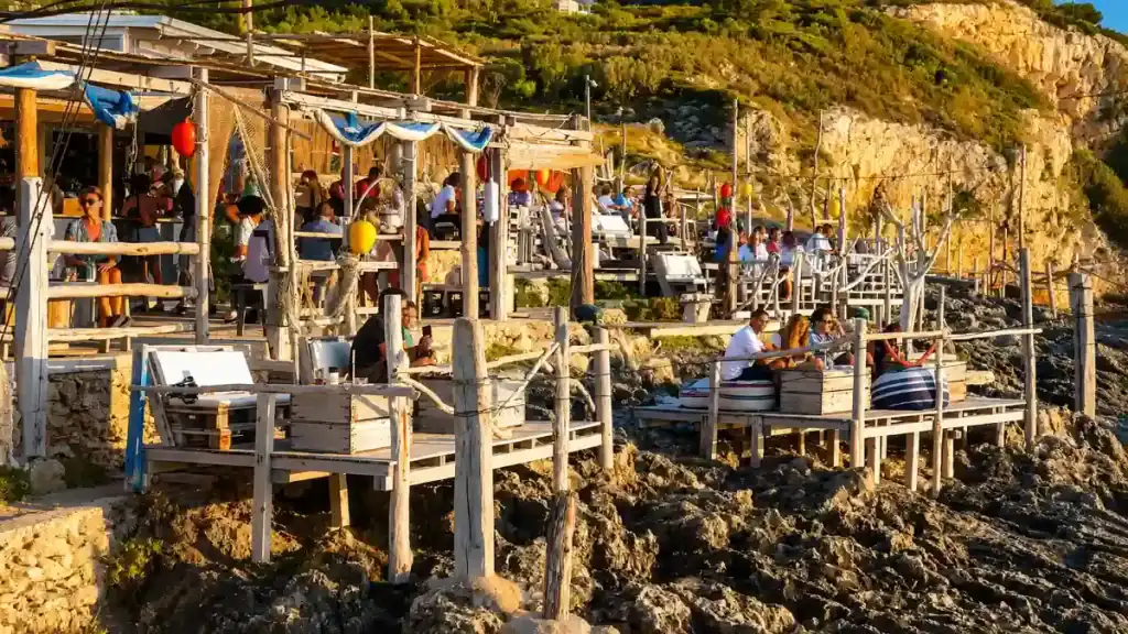 Diners on wooden stilted platforms at Al Trabucco da Mimì in Peschici, Gargano Puglia beach coastline.