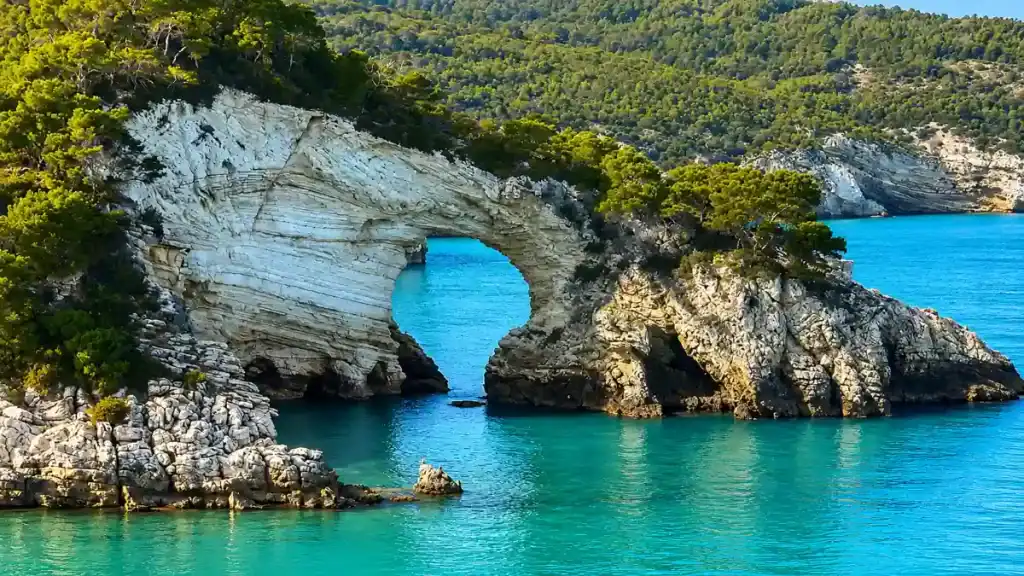 Natural limestone arch of San Felice rising from turquoise water along the Gargano coast.