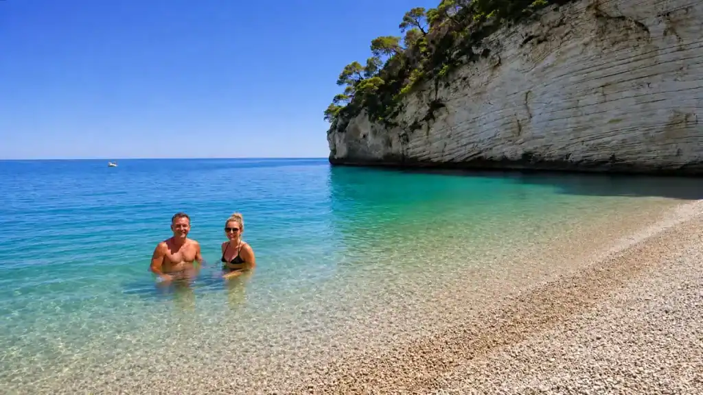Couple wading in turquoise shallows at Baia delle Zagare, one of the standout Gargano Puglia beaches.