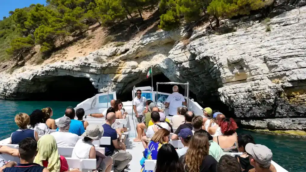 Tour boat passengers approaching sea caves near Vieste on a Gargano Puglia beaches excursion.