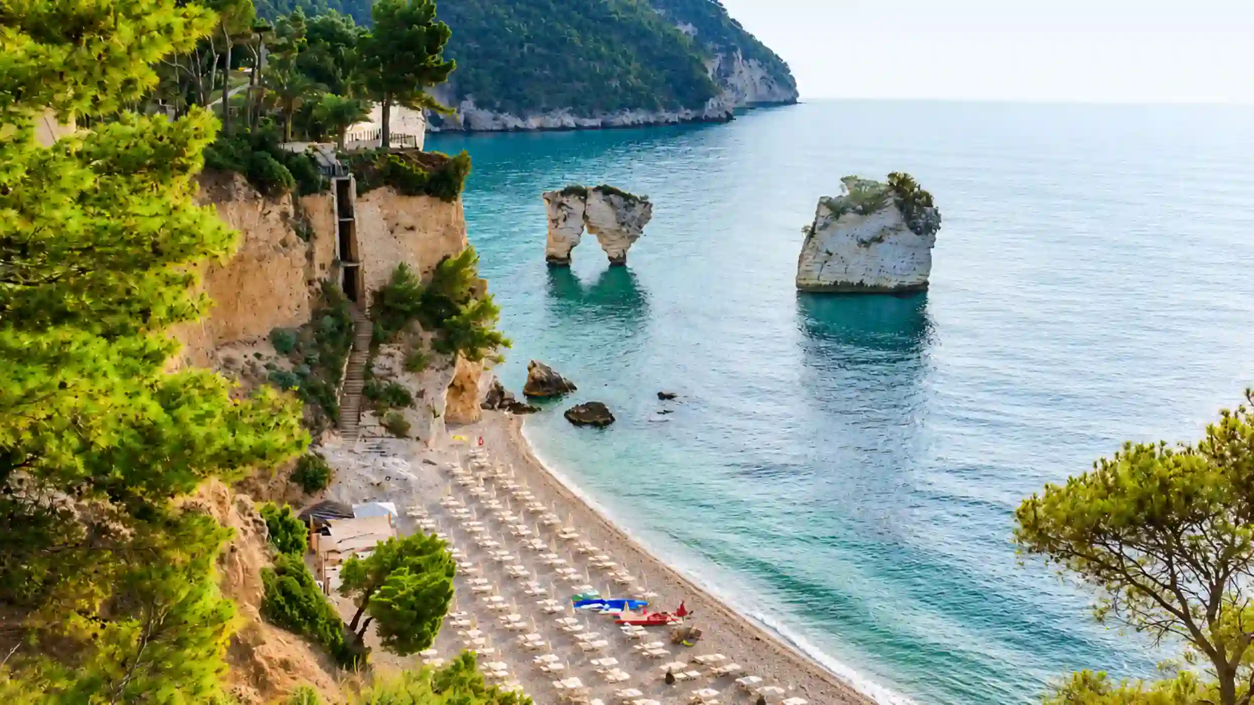 Faraglioni sea stacks rising off Baia delle Zagare beach in summer Gargano Puglia weather.
