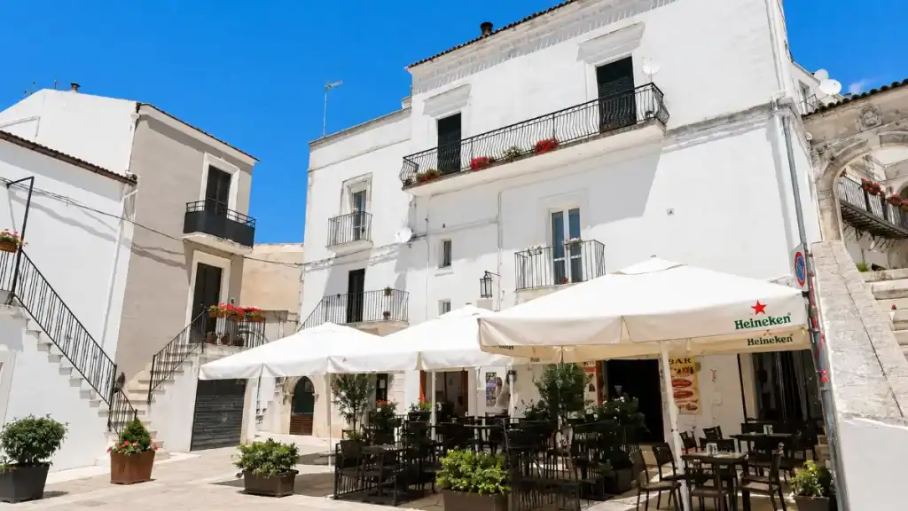 Café terrace with white parasols set against whitewashed houses in the Junno quarter.