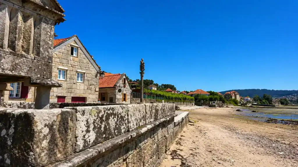 Granite houses and a stone cruceiro beside the tidal flats at Combarro