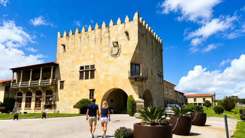 Couple approaching the crenellated stone tower of the Parador de Baiona