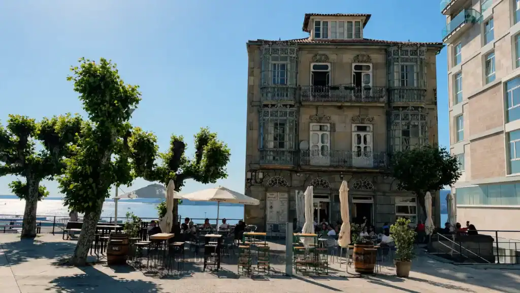 Terrace tables outside El Castro restaurant beside Vigo's waterfront on a sunny day
