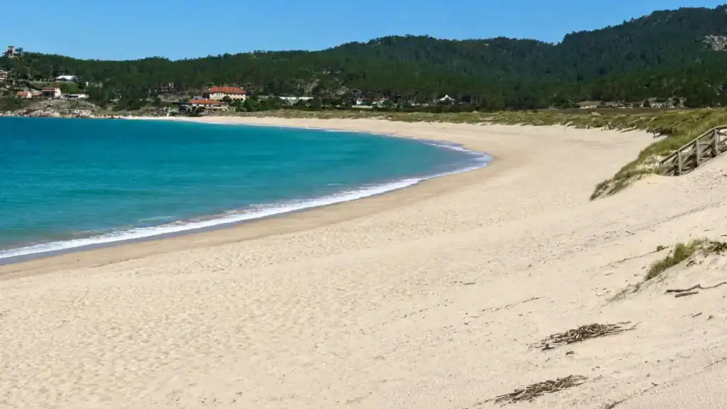Wide empty sand and turquoise water curving along Praia de A Lanzada in Galicia