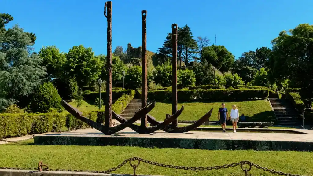 Three large iron anchors monument in Parque do Castro with Vigo castle ruins behind