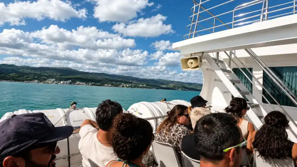 Ferry passengers looking out at the wooded Gargano shoreline from the open deck.