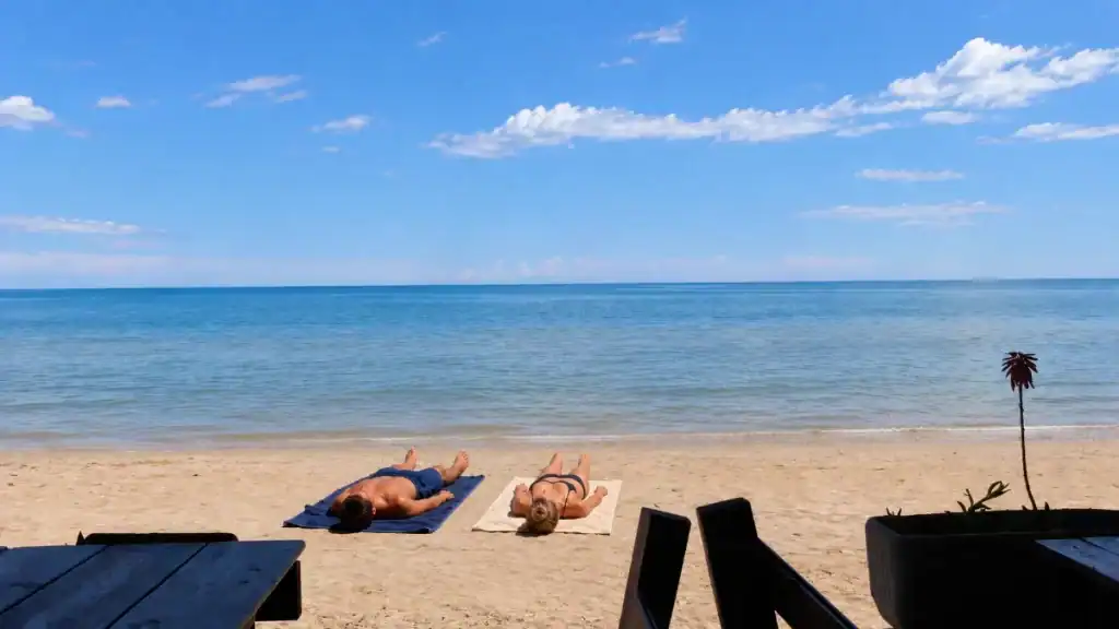 Two sunbathers lying on towels facing the calm Adriatic at Sfinalicchio beach.
