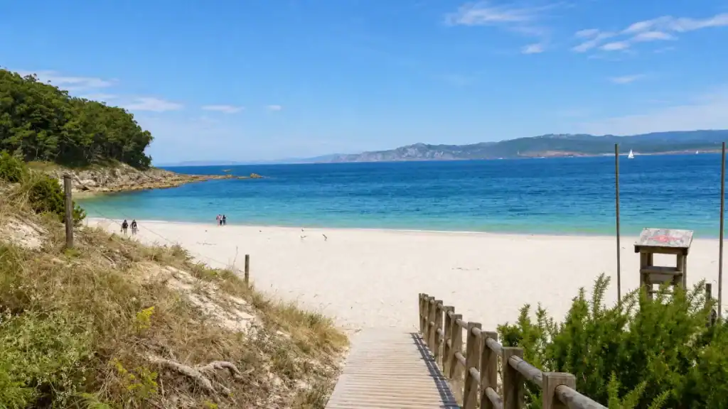 Wooden boardwalk leading down to Praia de Figueiras with turquoise water and Galician coast beyond