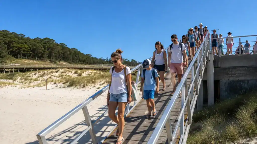 Long queue of visitors descending the jetty ramp onto Praia de Rodas dunes in summer