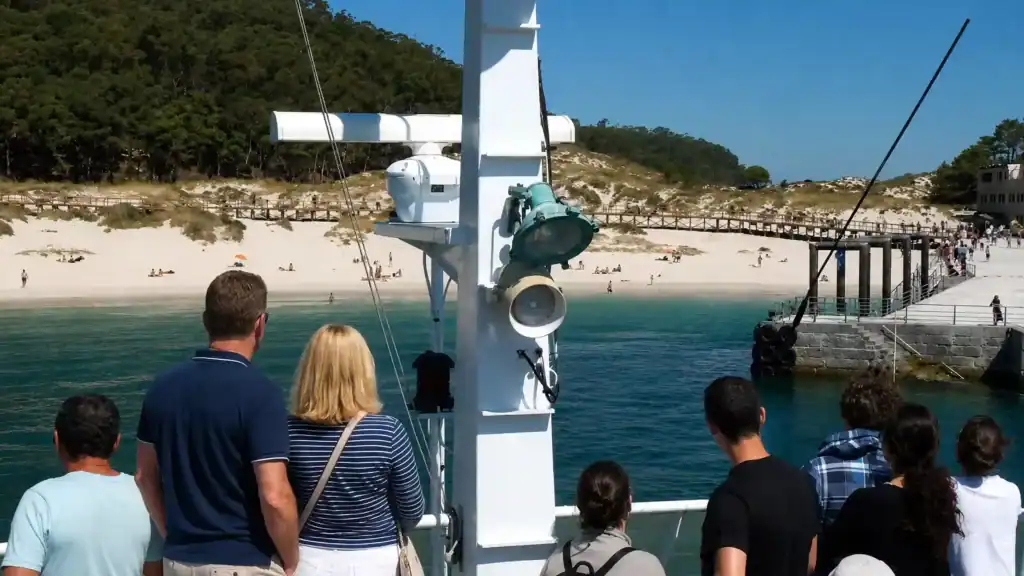 Passengers on ferry deck approaching Cíes Islands pier with white sand beach beyond