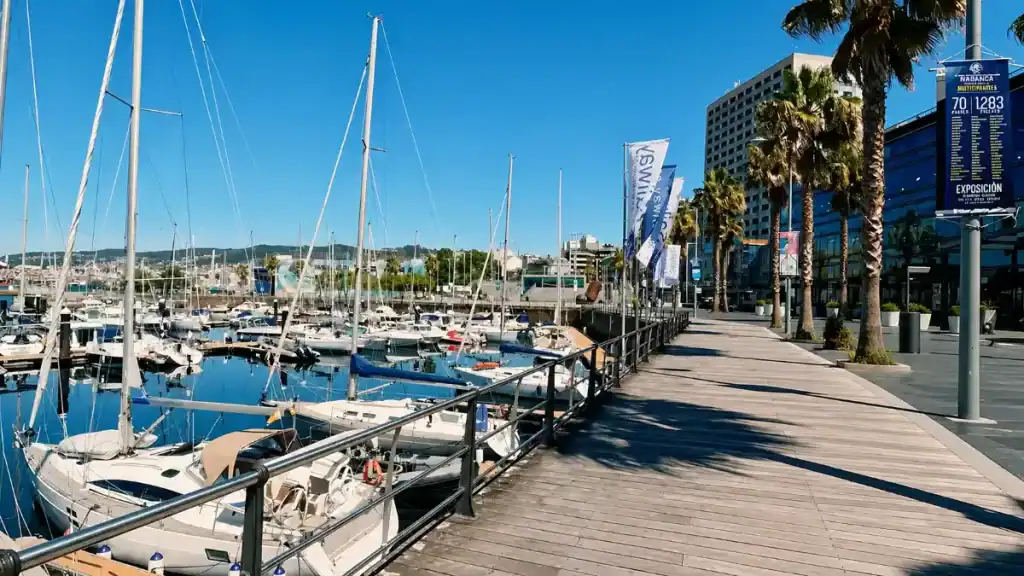 Sailboats moored along the timber boardwalk at Vigo marina on a clear summer day