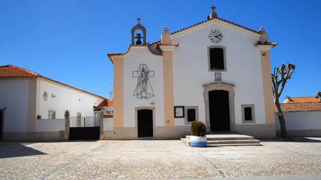 Twin bell towers and clock face on the parish church facing Almoçageme's main square.