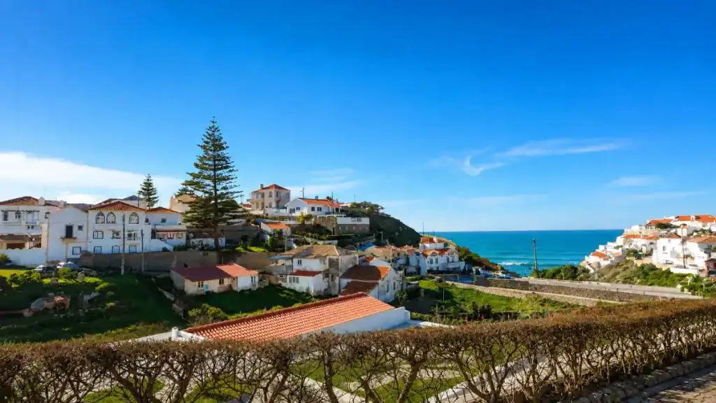 Whitewashed houses with terracotta roofs cluster on the cliffs at Azenhas do Mar.