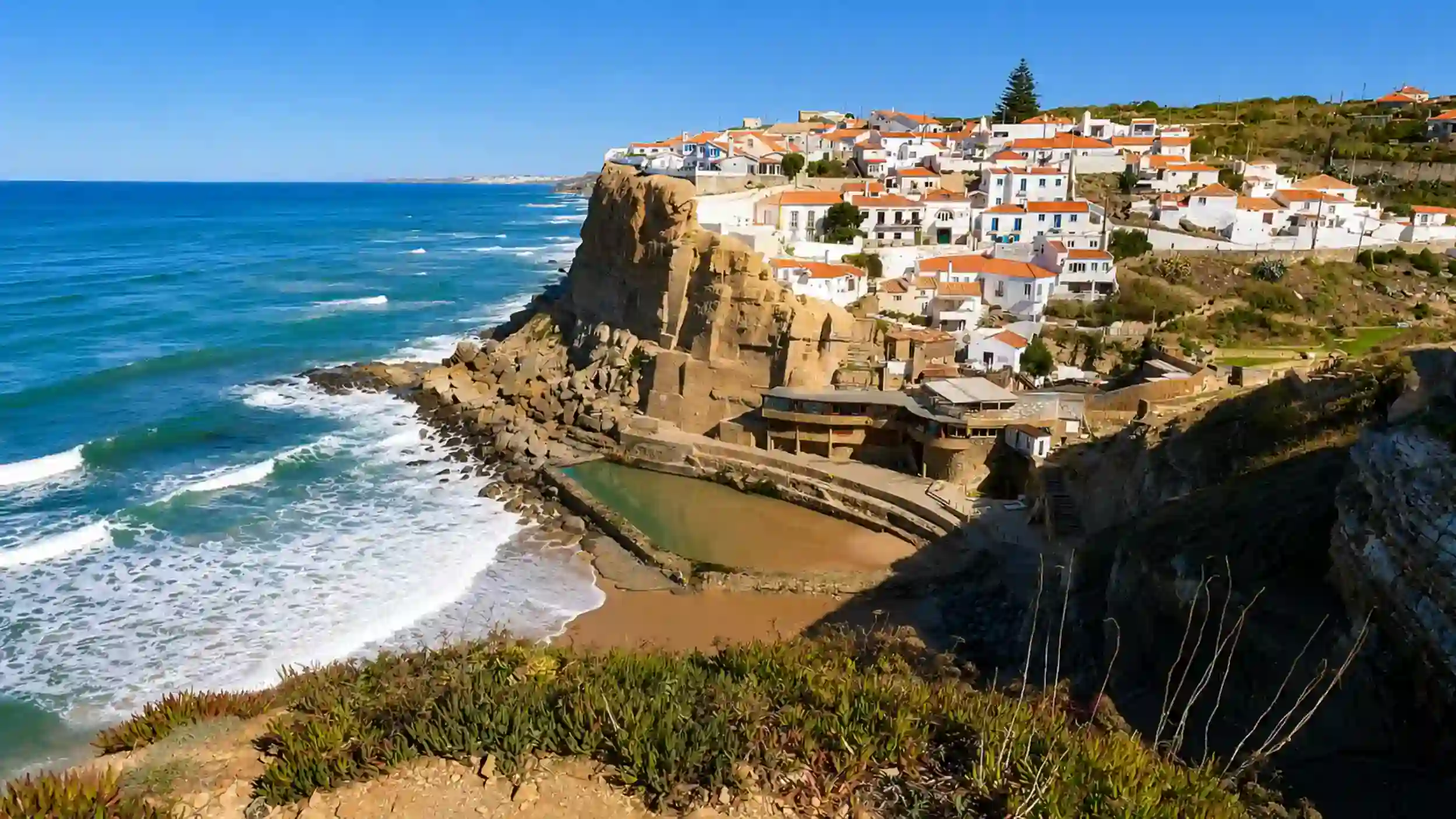 White-washed village of Azenhas do Mar clinging to Atlantic cliffs above a natural rock pool