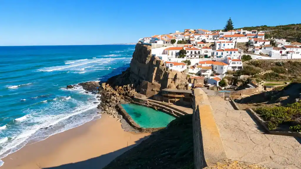 Azenhas do Mar turquoise rock pool sits below whitewashed houses on the cliff edge.