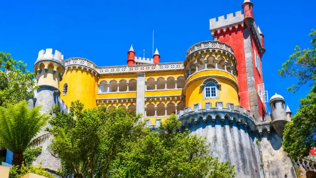 Pena Palace yellow and red towers rising above treetops, one of the beautiful places around Sintra