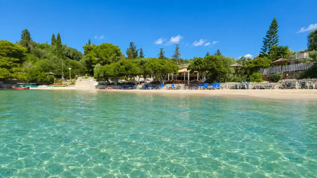 Blue loungers and a beachfront taverna sit behind rippled shallows at Mongonissi.