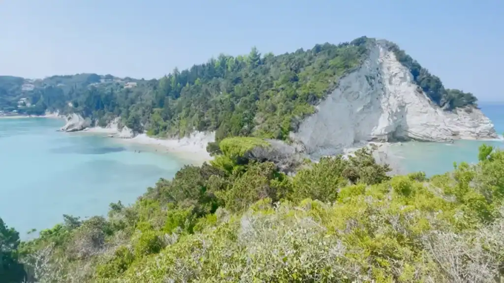 Bare rock cliffs rise above a hidden cove on the hike toward Komeno Beach.