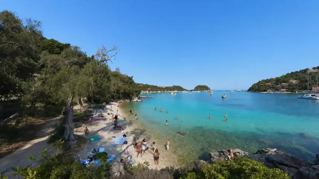 Sunbathers and turquoise water fill the shoreline at Kanoni Beach, one of the best beaches in Paxos.