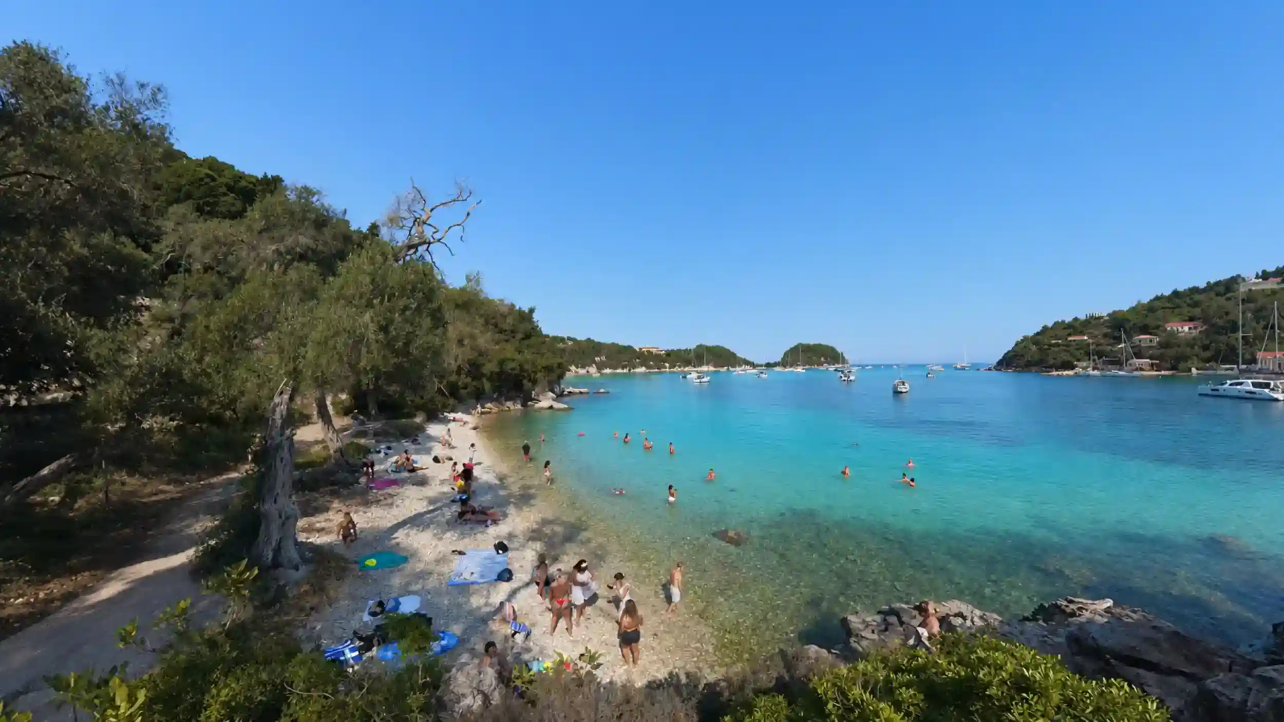 Sunbathers and turquoise water fill the shoreline at Kanoni Beach, one of the best beaches in Paxos.