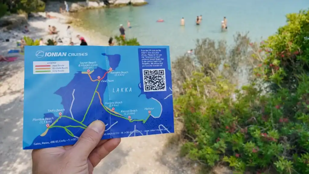 Hand holds a Lakka walking map marking trails to some of the best beaches in Paxos.