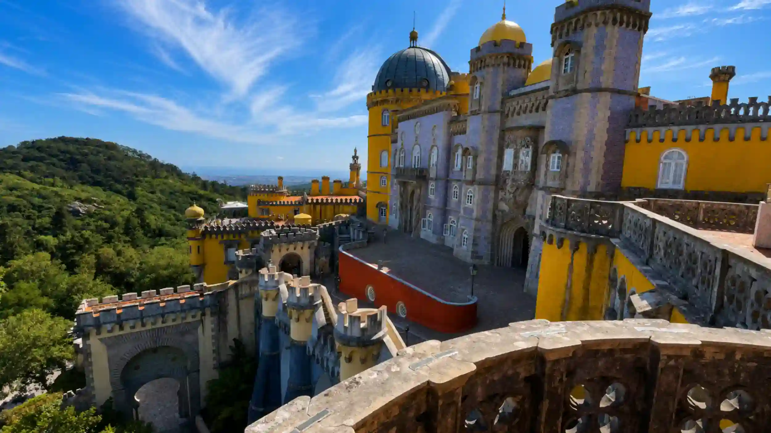 Yellow and lilac towers of Pena Palace among Sintra's hilltop forest, one of the best places in Sintra