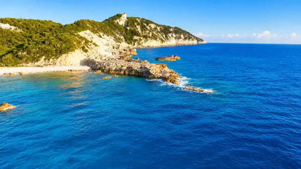 Rocky headland juts into deep blue water near Plani Beach.