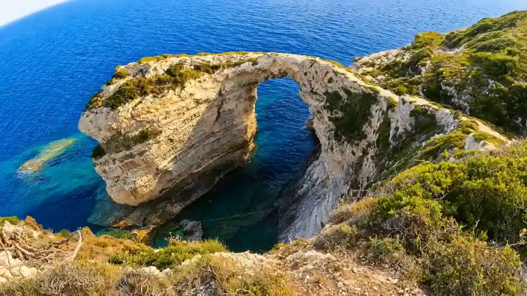 A natural stone arch spans deep blue water at Tripitos.