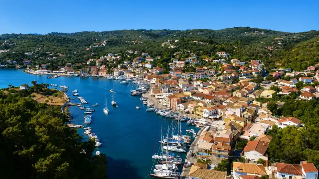 Aerial view of Gaios town wrapped around a curving inlet dotted with anchored yachts