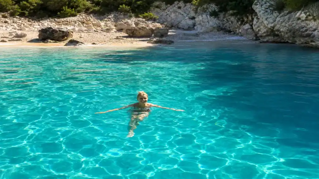 Swimmer floating in clear turquoise water off a rocky cove near Lakka.