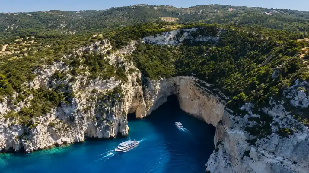 Boats passing through a limestone sea cave along the western coast of Paxos.