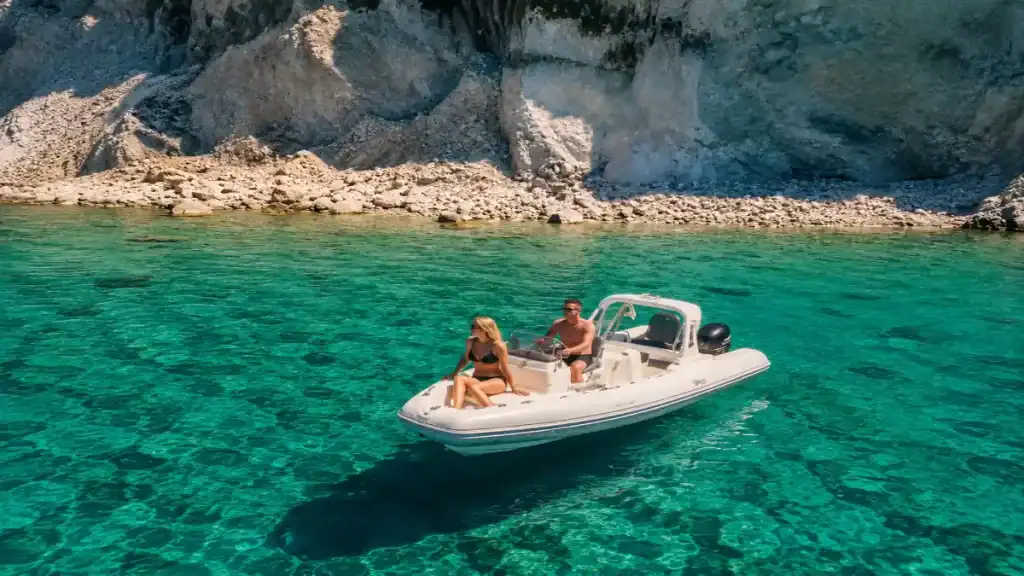 A couple rests aboard a rib boat anchored beside limestone cliffs at Erimitis, Paxos