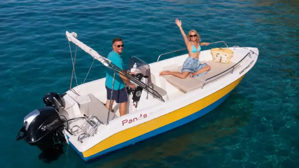 Couple aboard a hired motorboat named Panos in clear coastal waters.