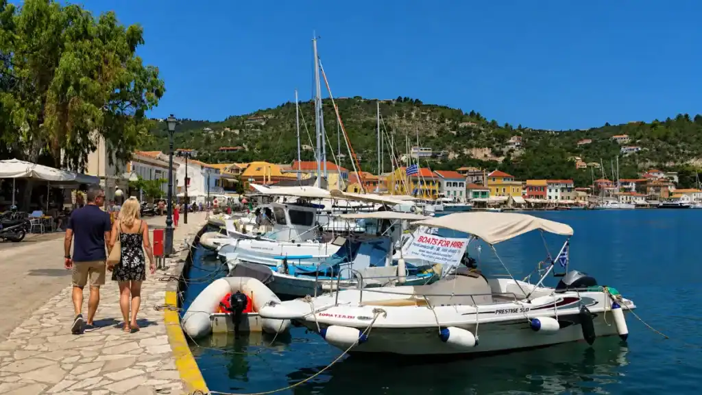 A couple stroll the Gaios waterfront past hire boats, one route for how do you get to Paxos.