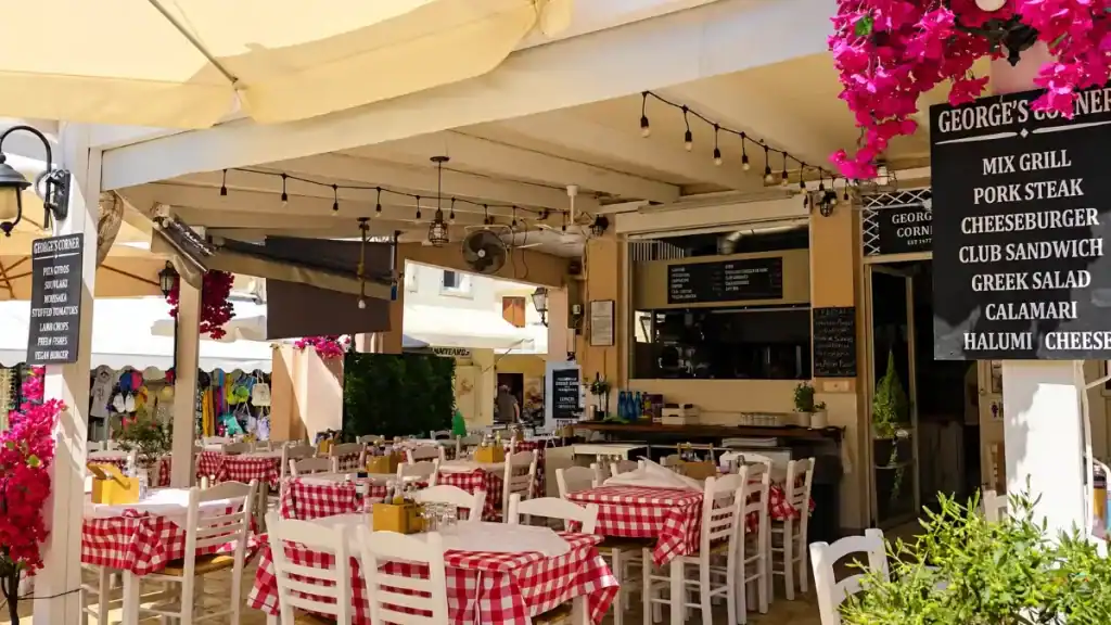 Red gingham tables sit empty at George's Corner taverna in Gaios, bougainvillea draping overhead.