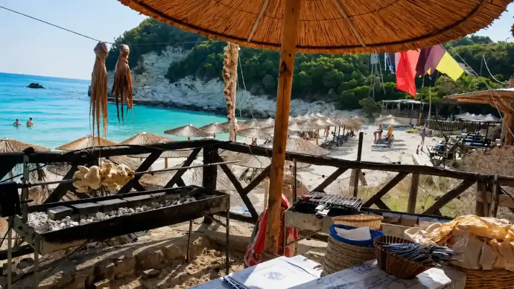 Fresh octopus drying beside a grill at Captain Spiros taverna, overlooking Voutoumi Beach umbrellas.