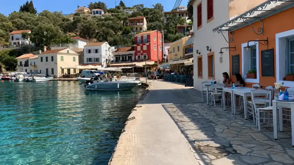 Colourful pastel buildings and moored boats line the harbourfront promenade at Loggos.