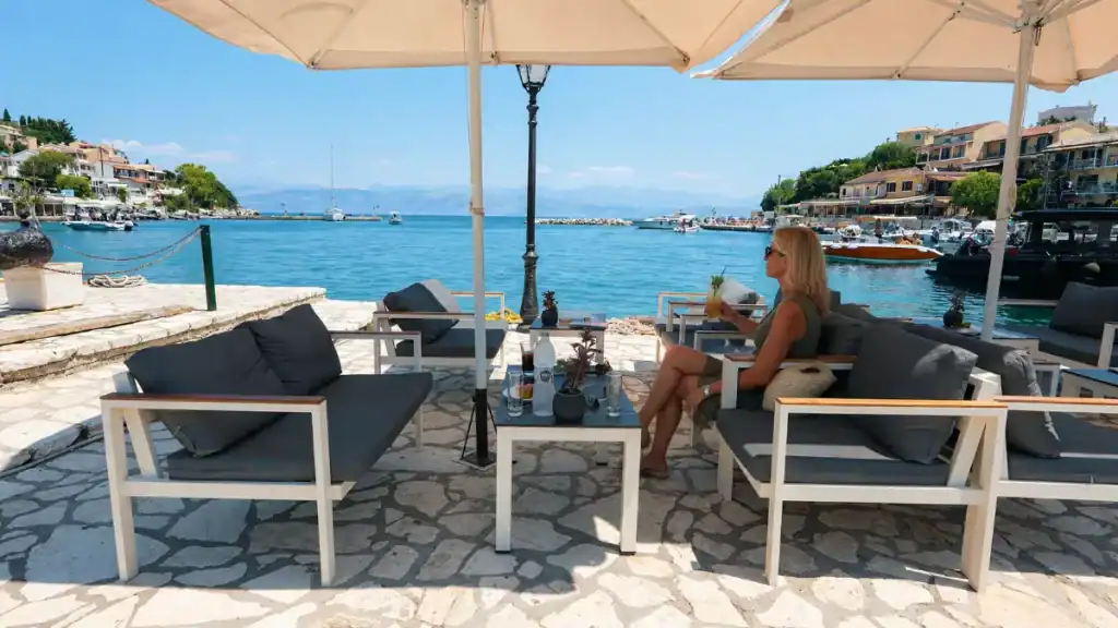 A woman relaxes under a shade umbrella beside the harbour in Kassiopi