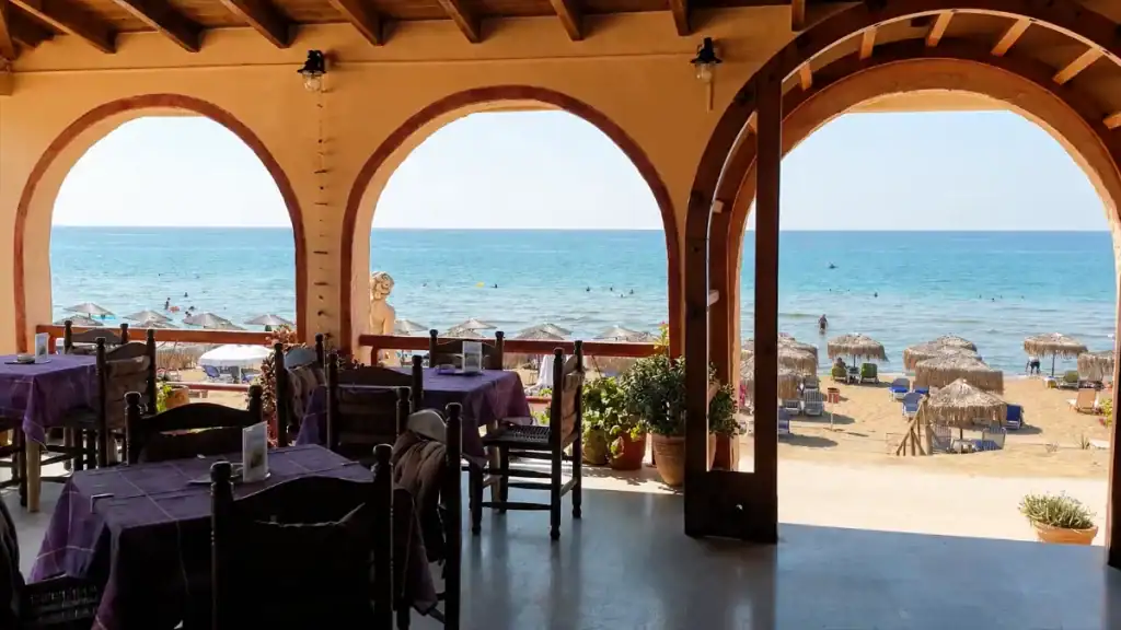 Arched terrace tables overlook the sandy beach at Taverna Julia