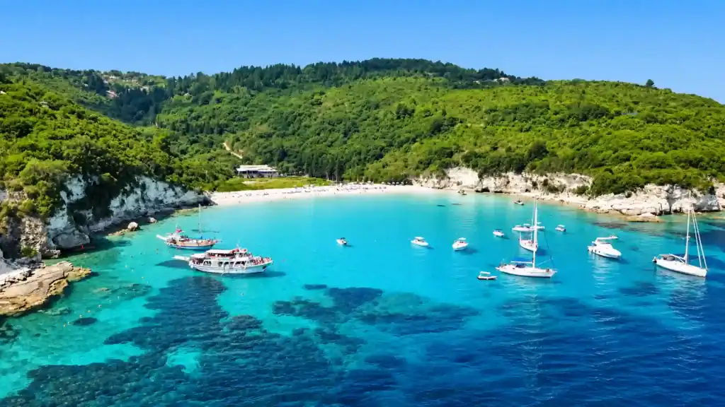Sailboats anchor in turquoise water at Voutoumi Beach near Paxos or Corfu