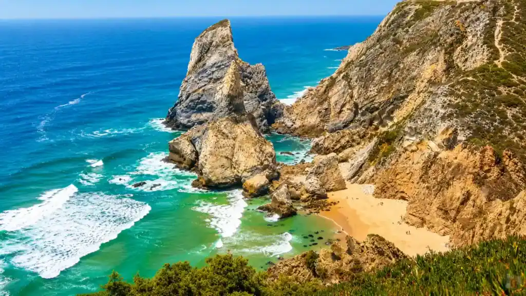 Jagged sea stack rising from the Atlantic at Cabo da Roca with a small cove below