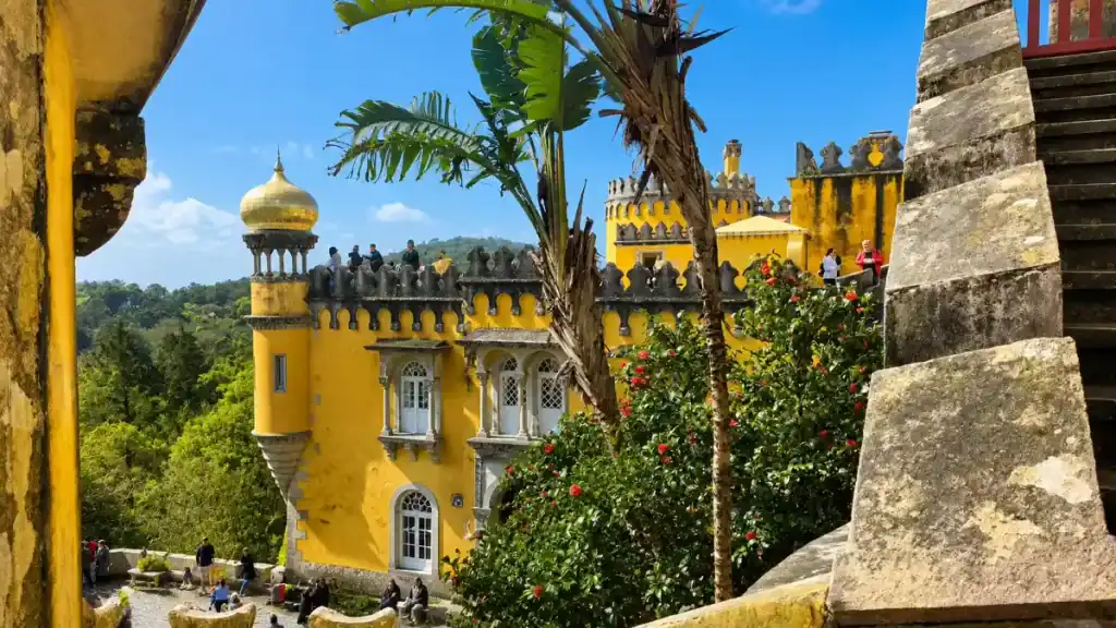 Yellow towers and Moorish dome of Pena Palace framed by stone archway, one of the most visited places around Sintra.