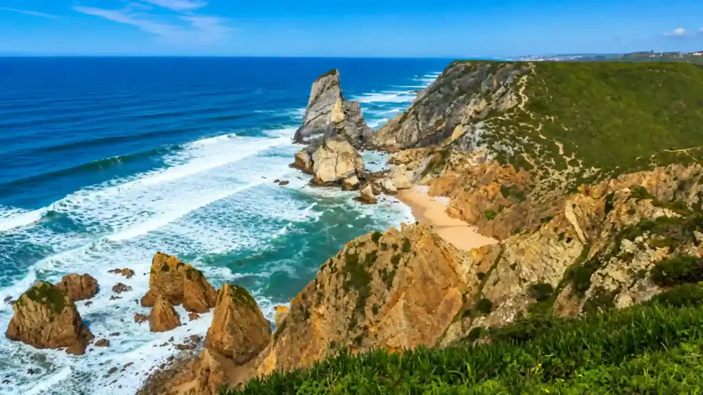 Jagged sea stack rises beside a hidden beach at Cabo da Roca, perfect spot to visit Cabo da Roca.