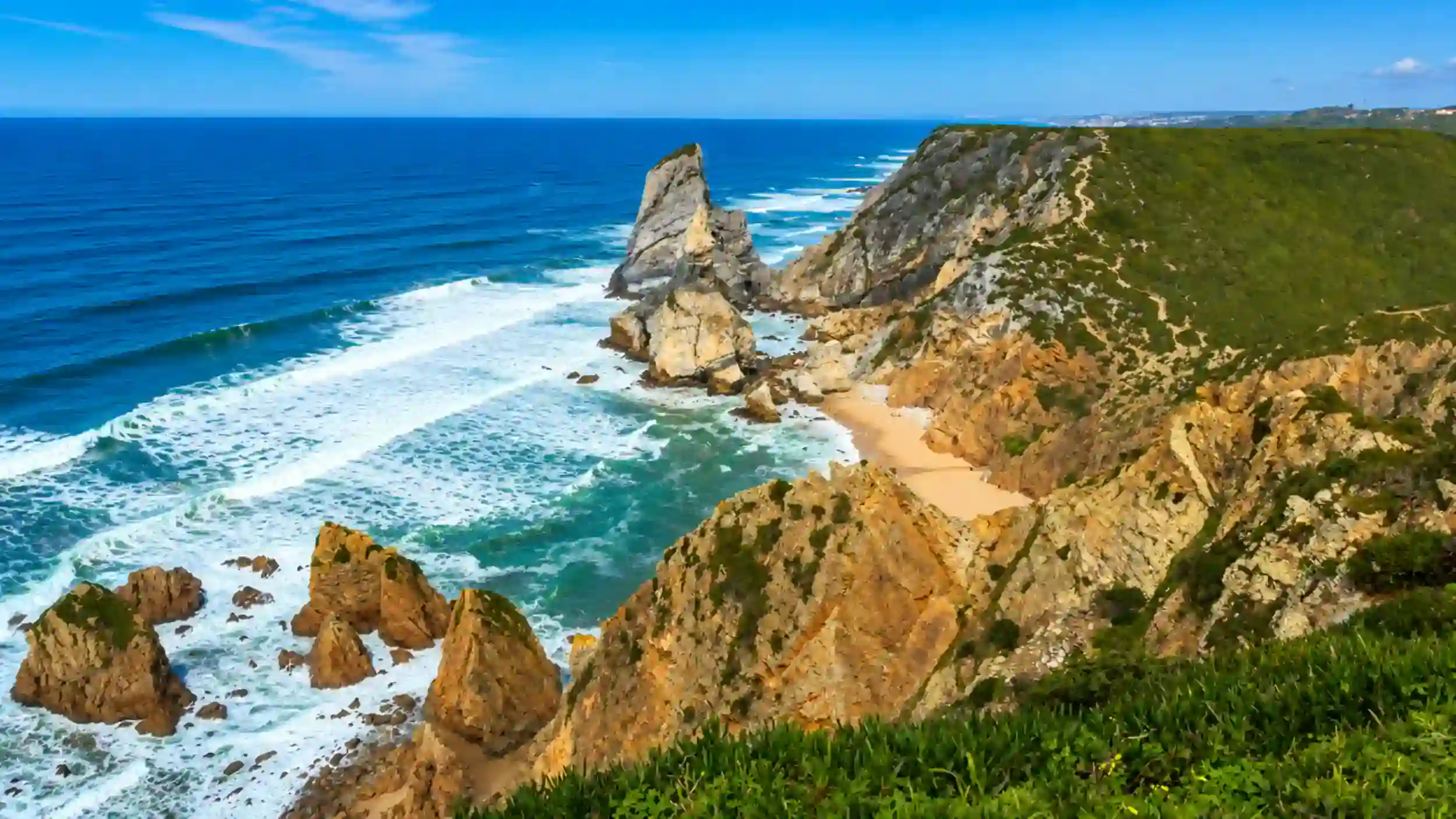 Jagged sea stack rises beside a hidden beach at Cabo da Roca, perfect spot to visit Cabo da Roca.